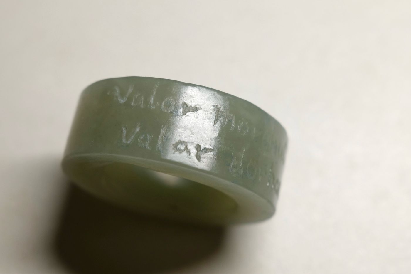 A carved stone ring engraved with text around its band, on a plain background